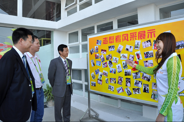 志愿者为仲伟合校长介绍志愿者风采展板