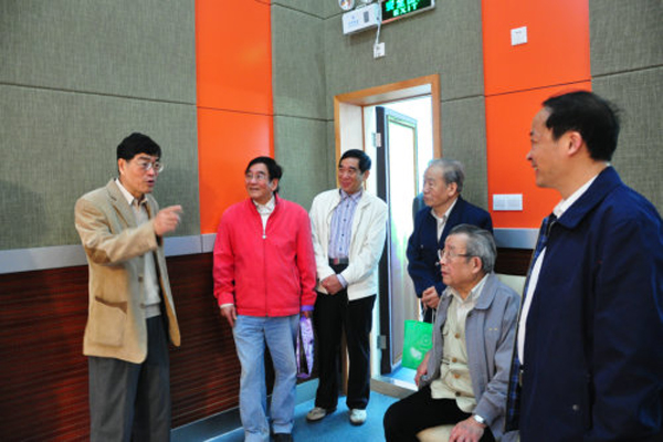 徐真华与新闻学院院长郭光华向离退休老同志介绍实验室的使用情况