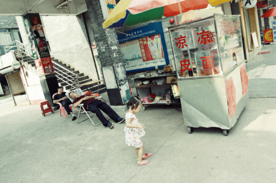 午后的安逸时光:摊主小憩,小女孩独自玩乐。 午后的安逸时光:摊主小憩,小女孩独自玩乐。
