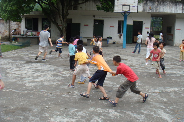 老师与学生在操场上玩老鹰捉小鸡